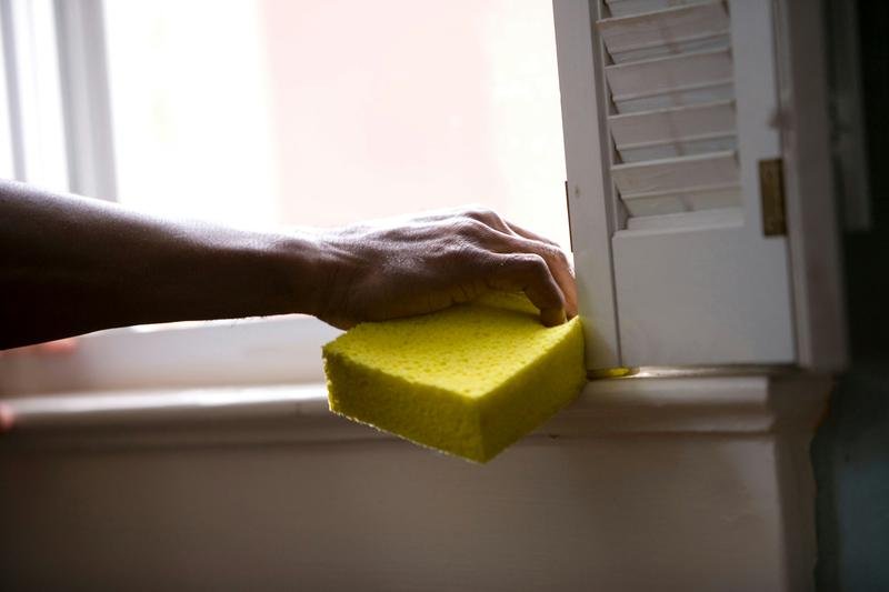 A cleaner wiping a painted window sill