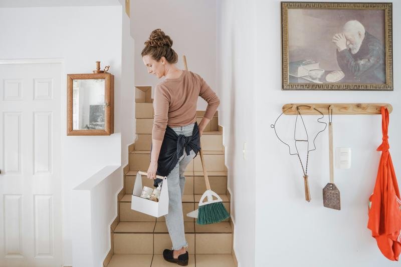 A cleaner carrying a caddy of products up a flight of stairs